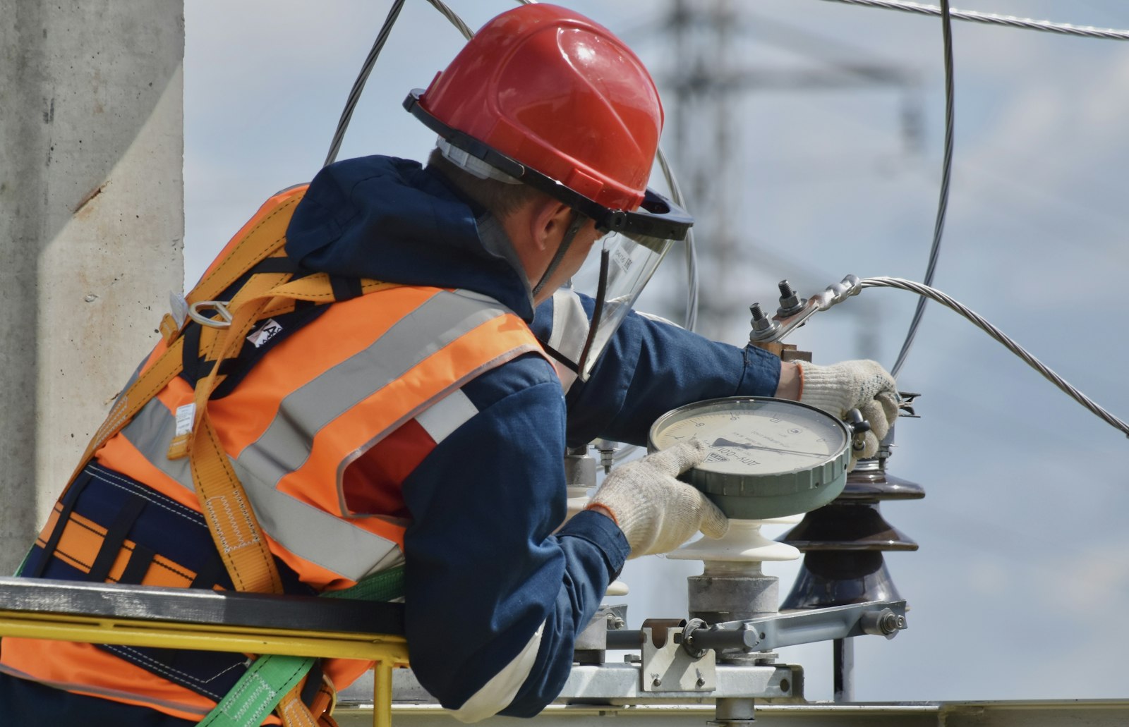 Field technician in hard hat and hi-vis working on equipment on site